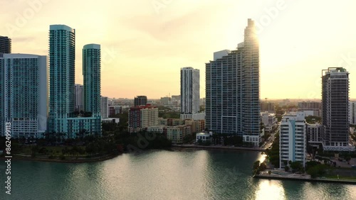 Captivating aerial view of Miami skyline and waterfront during a stunning golden sunset, with buildings reflecting in the calm bay, creating a mesmerizing scene of beauty and tranquility. 4k footage