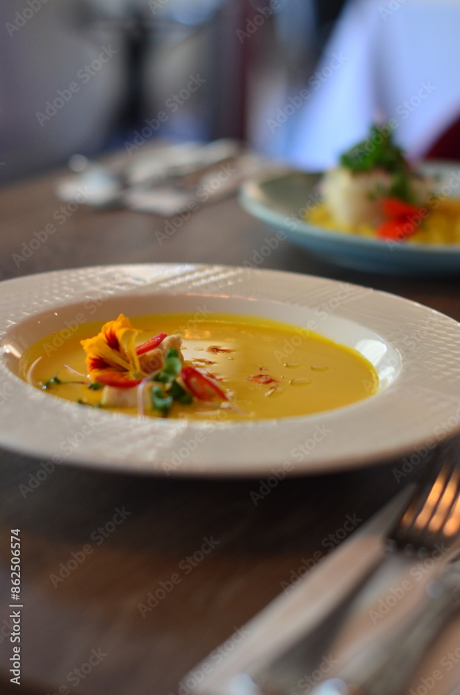yellow vegetable soup with herbs, squid, pumpkin soup, herbs, plate, serving restaurant table, lunch menu 