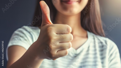 Close-up of young adult giving thumbs up gesture photo