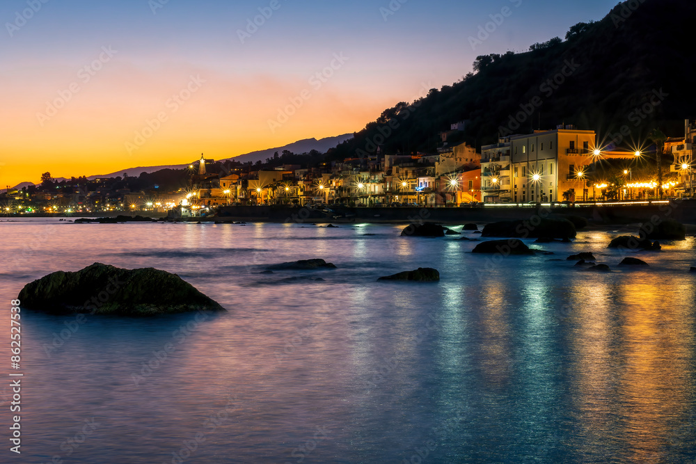 evening or night landscape of evening town coastline in golden lights and sea gulf with calm water and nice reflections with beautisul sunset sky on background evening or night landscape of evening town coastline in golden lights and sea gulf with calm water and nice reflections with beautisul sunset sky on background