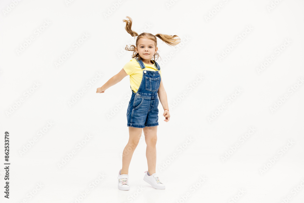 Little girl dancing in the studio on a white background. Happy energetic girl having fun and enjoying her childhood. Concept of fashion, style and happy children's emotions. Little girl dancing in the studio on a white background. Happy energetic girl having fun and enjoying her childhood. Concept of fashion, style and happy children's emotions.