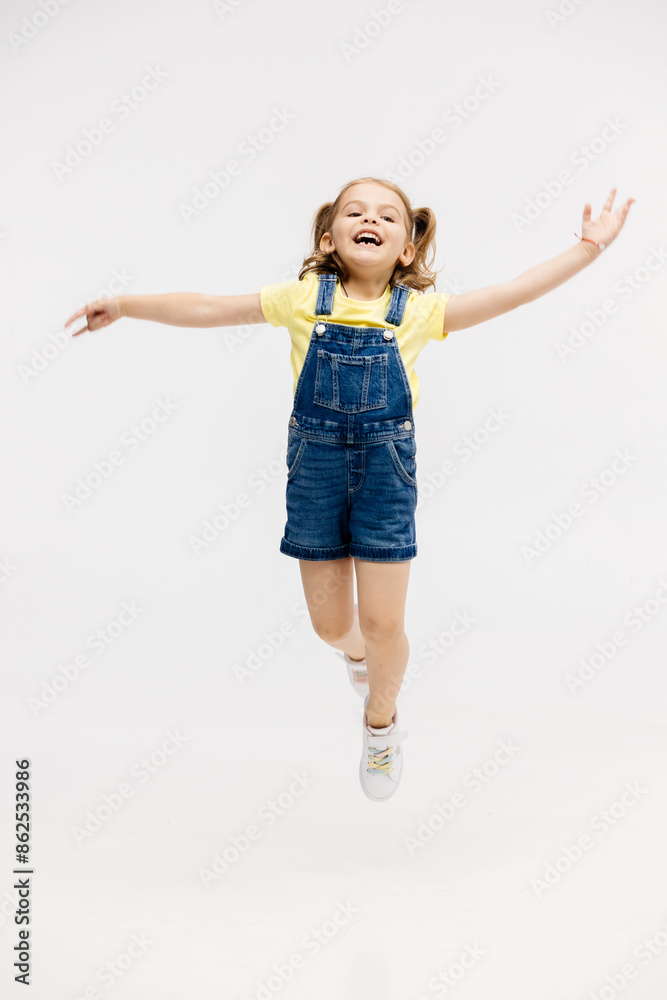 Little girl dancing in the studio on a white background. Happy energetic girl having fun and enjoying her childhood. Concept of fashion, style and happy children's emotions. Little girl dancing in the studio on a white background. Happy energetic girl having fun and enjoying her childhood. Concept of fashion, style and happy children's emotions.