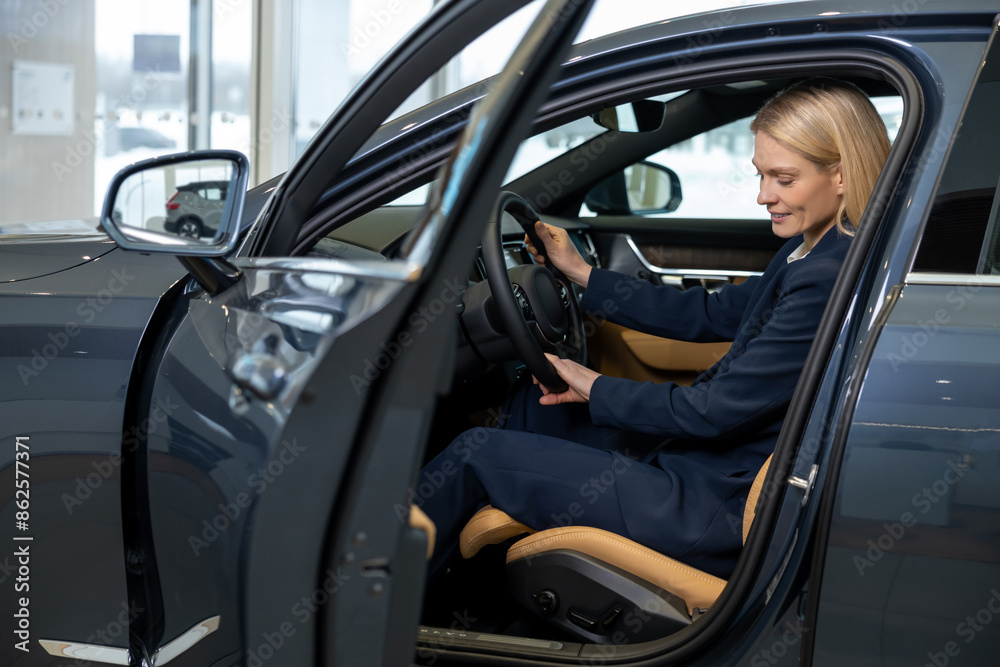 Pretty business woman sitting in a car and looking contented Pretty business woman sitting in a car and looking contented