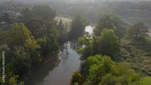 Bayou river with sun reflections behind trees on a foggy morning photo