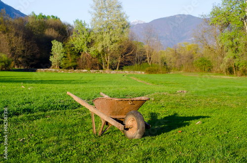 Wheelbarrow on a Green Field with Mountain View in a Sunny Day in Locarno, Ticino, Switzerland. photo