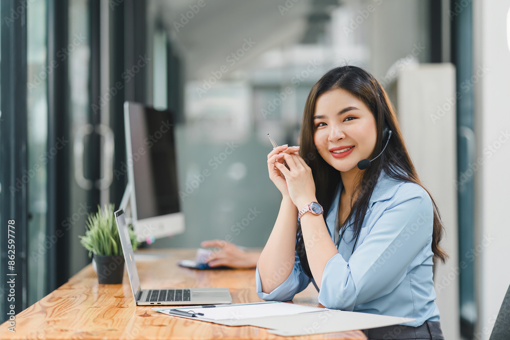 Confident asian young woman call center operator wearing headphones with a microphone. Confident asian young woman call center operator wearing headphones with a microphone.