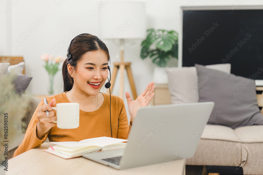 Woman wearing a headset, actively engaged in an online learning session with a teacher displayed on a computer screen, studying from home.