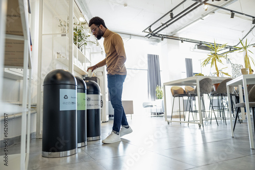 Young man in casual clothes throwing waste to the recycle bin photo