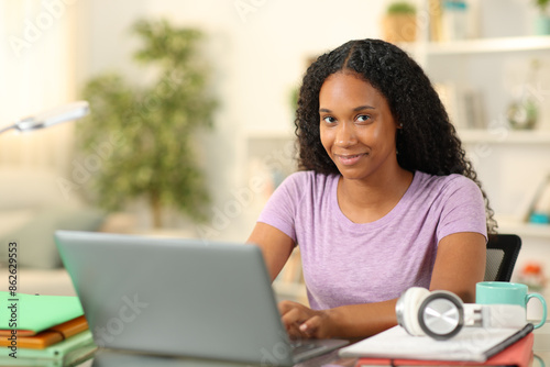 Black proud student using laptop looking at camera