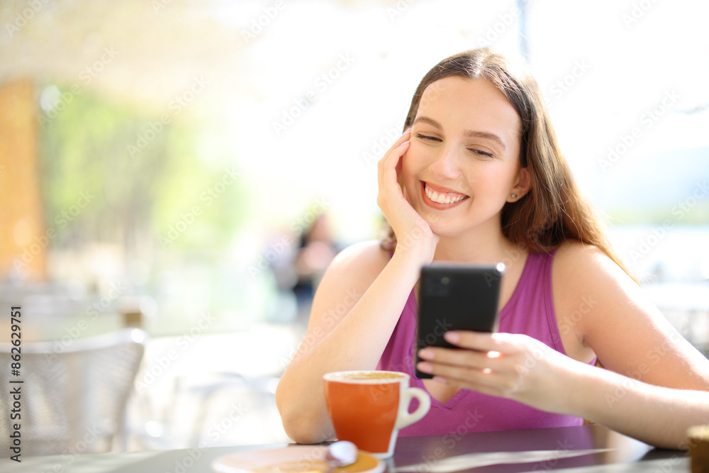 Happy woman checking phone in a restaurant Happy woman checking phone in a restaurant