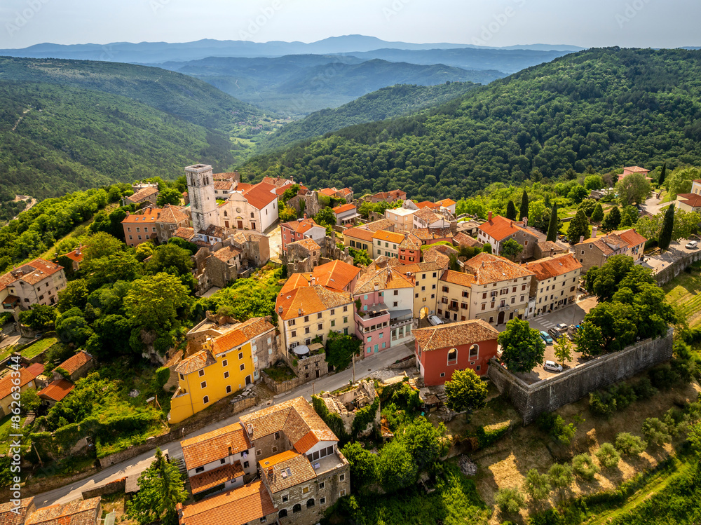 Aerial view of quaint village rooftops and historic church nestled among Mediterranean hills in Oprtalj, Istria, Croatia. Aerial view of quaint village rooftops and historic church nestled among Mediterranean hills in Oprtalj, Istria, Croatia.