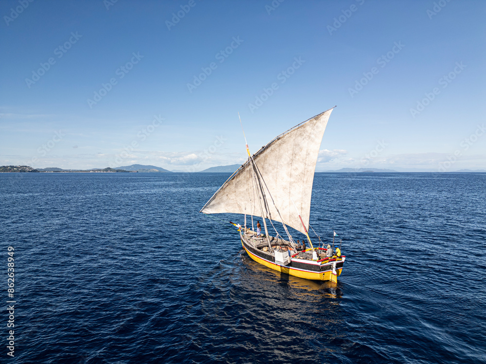 Nosy Be, Madagascar - 21 June 2023: Aerial view of Dhow boat sailing on calm ocean, Nosy Be, Madagascar. Nosy Be, Madagascar - 21 June 2023: Aerial view of Dhow boat sailing on calm ocean, Nosy Be, Madagascar.
