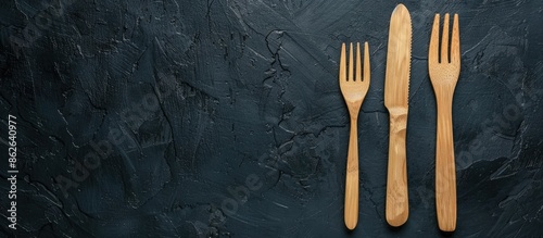 Eco-friendly wooden knife and fork on a black background with copy space image for text, emphasizing the zero-waste concept in a top view.