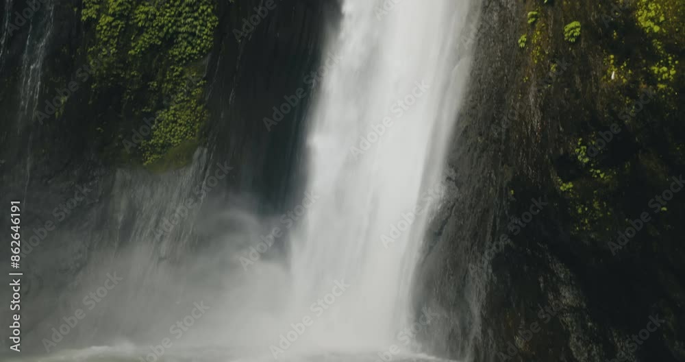 Tourist girl standing near powerful jungle waterfall. Long hair blows in wind. Tourism, trekking, hiking, relax, active lifestyle, summer holiday vacation on Bali. Slow motion 4K back view zoom in Tourist girl standing near powerful jungle waterfall. Long hair blows in wind. Tourism, trekking, hiking, relax, active lifestyle, summer holiday vacation on Bali. Slow motion 4K back view zoom in