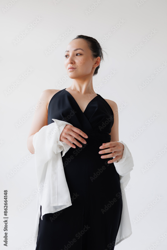 Stylish asian woman in black jumpsuit and shirt posing isolated on grey Stylish asian woman in black jumpsuit and shirt posing isolated on grey