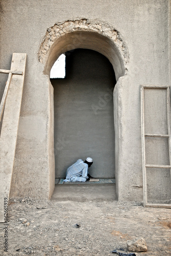 Djenne, Mali - 09 October 2010: View of Muslim man praying at rustic Djenne Mosque, Inland Niger Delta, Mali. photo