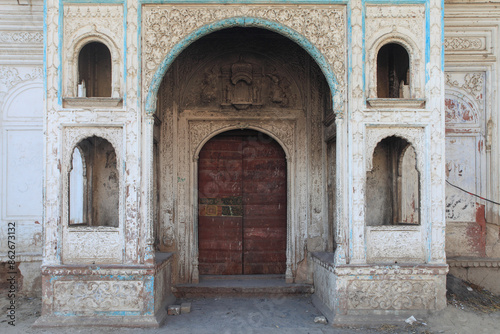 View of ornate ancient entrance with wooden door and arched doorway, Sadiq Ghar Palace, Dera Nawab Sahib, Punjab, Pakistan.