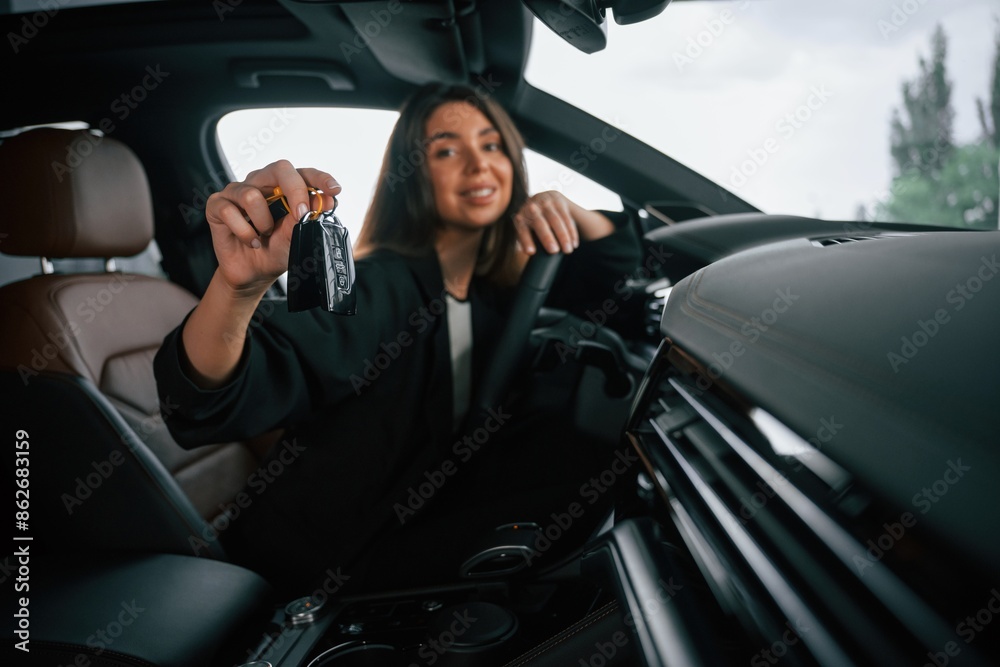Cheerful, happy new owner with keys. Beautiful businesswoman is in the new car Cheerful, happy new owner with keys. Beautiful businesswoman is in the new car