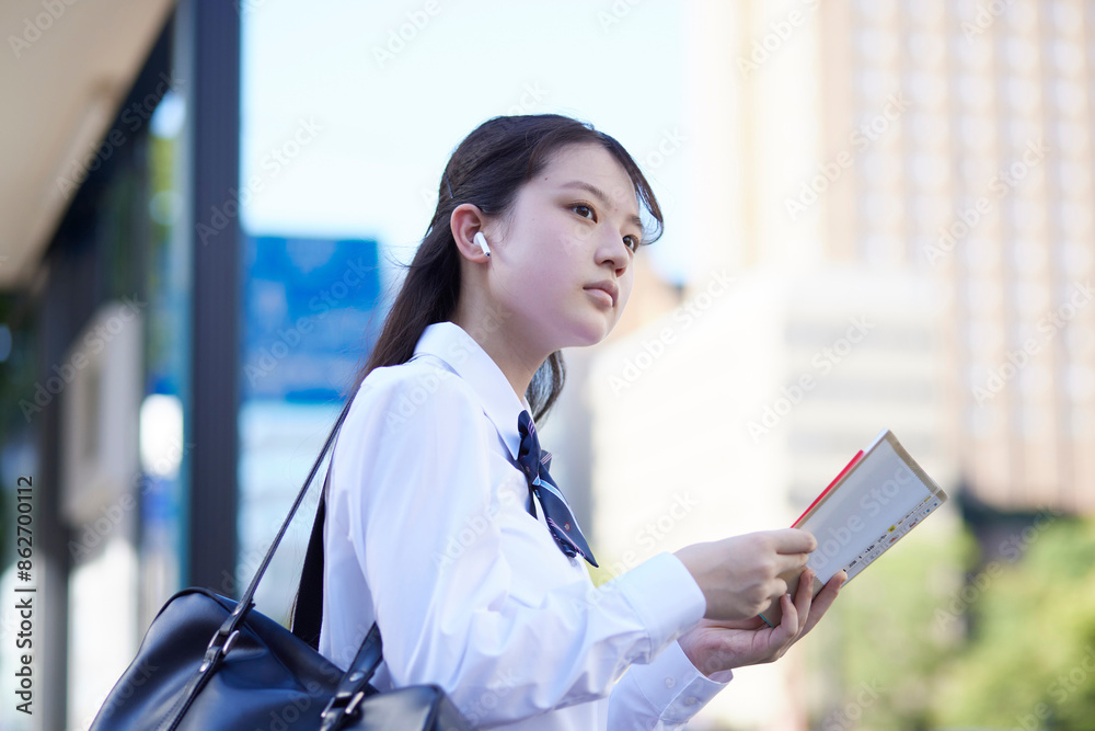 バス停にて参考書で勉強をする女子高校生