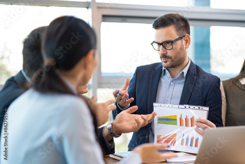 Foto Businessman advising clients while reviewing a document with graphs and diagrams
