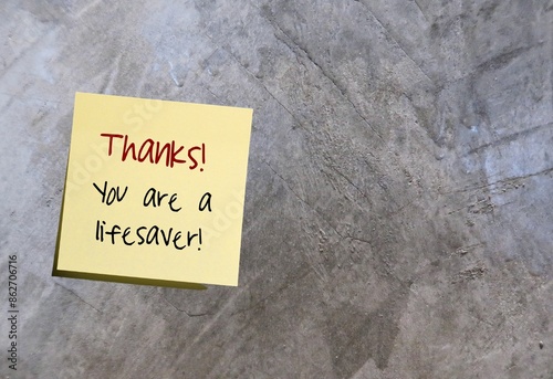 Yellow note on cement background with handwriting THANKS YOU ARE A LIFESAVER, thank you ,appreciation note for someone for being helpful in very difficult situation or critical moment