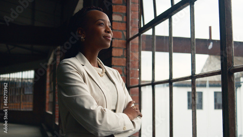 Confident Businesswoman Looking Through Window in Modern Industrial Office