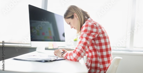 Obraz na płótnie Hunched woman typing on computer keyboard at table