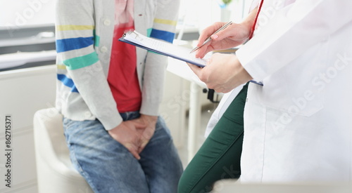 Photos Man sitting at doctor appointment and holding on to genital area closeup