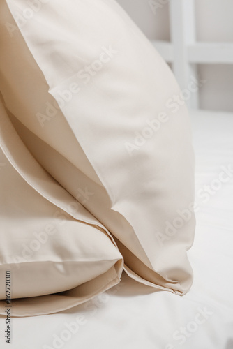 Beige satin (lyocell, silk, polyester) pillowcases on the bed. Home textile. photo