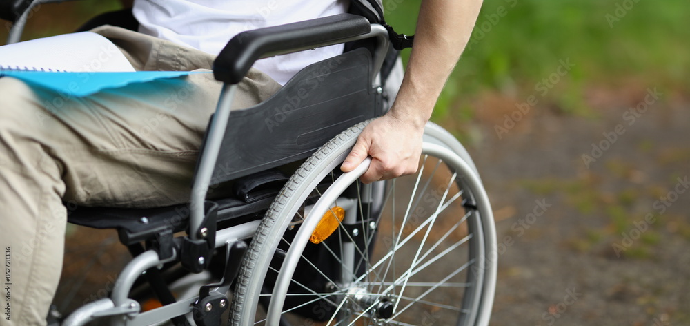 Man in wheelchair holds wheel with his hand. Rehabilitation of people with disabilities concept Man in wheelchair holds wheel with his hand. Rehabilitation of people with disabilities concept