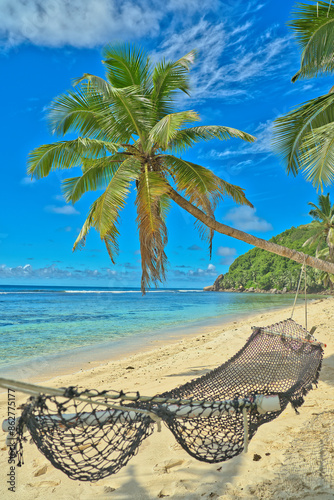 Anse Parnel beach, blue sky turquoise water, low tide sunny day, white sandy beach, coconut palm trees and hammock, Mahe, Seychelles photo