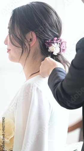 Vertical video of bride and hair and makeup artist preparing for wedding hair set and pre-shoot in a beautifully backlit room. photo
