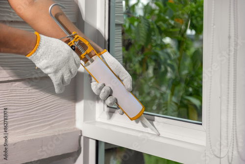 Bild auf Leinwand Construction worker using silicone sealant caulk for repair leaked inside window frame