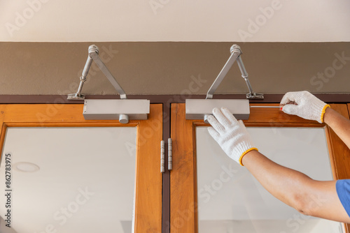 Foto Handyman fixing door closer and adjust  hydraulic arm extended.