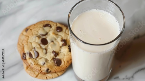A detailed overhead look at a chilled glass of milk next to two tasty chocolate chip cookies