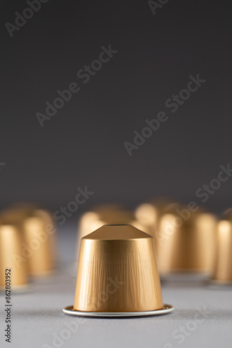 gold coffee capsules arranged on a neutral background, modern design. Advertising