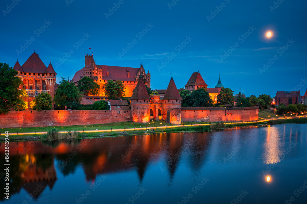 Castle of theTeutonic Order in Malbork by the Nogat river at night with full moon. Castle of theTeutonic Order in Malbork by the Nogat river at night with full moon.