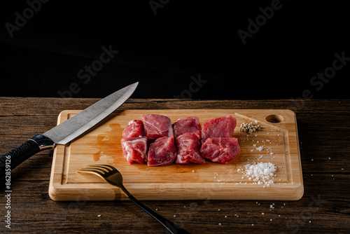 A slice of beef on a cutting board with a knife and fork