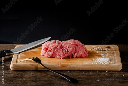 A slice of beef on a cutting board with a knife and fork