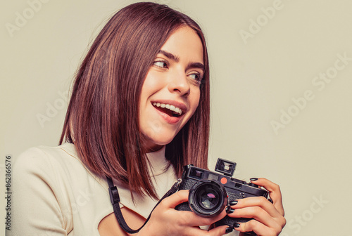 Portrait of young woman take pictures on retro vintage photo camera. Close up portrait of a smiling pretty girl taking photo on a camera isolated over gray background. Space for text photo