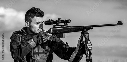 Hunter with hunting gun and hunting form to hunt. Hunter is aiming. Shooter sighting in the target. The man is on the hunt. Hunt hunting rifle. Black and white photo