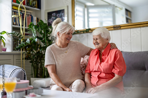 Happy senior woman with her adult daughter at home 