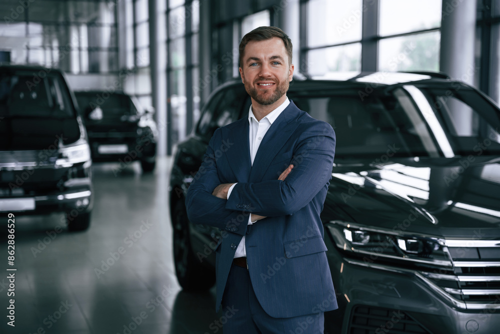 Cheerful salesman. Guy is in a car dealership Cheerful salesman. Guy is in a car dealership