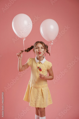 Two balloons and candy. Cute little girl is against pink background © standret