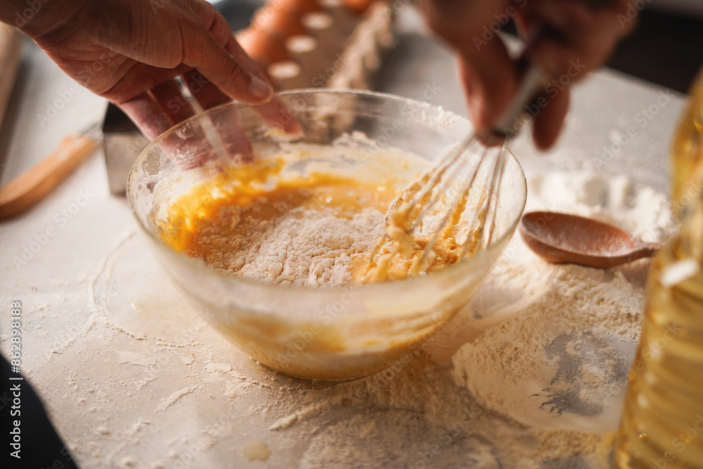 Baking preparation with flour and eggs being whisked in bowl by hand Baking preparation with flour and eggs being whisked in bowl by hand