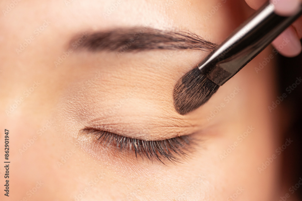 makeup artist using makeup brush for eyes and applying brown eyeshadow. make-up for young asian girl. makeup artist using makeup brush for eyes and applying brown eyeshadow. make-up for young asian girl.