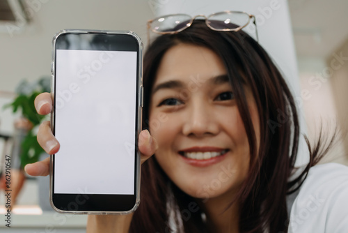 Asian Thai woman smiling and showing white empty screen on mobile phone.