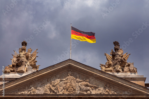 The national flag of Germany is on the roof of a building against the blue sky.