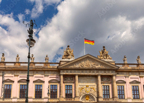 The national flag of Germany is on the roof of a building against the blue sky.