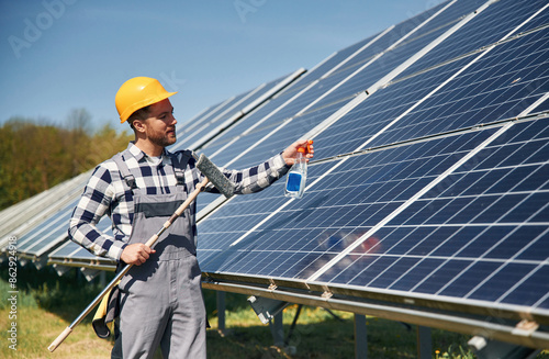 Procedure of cleaning the surface. Engineer with photovoltaic solar panels outdoors at daytime